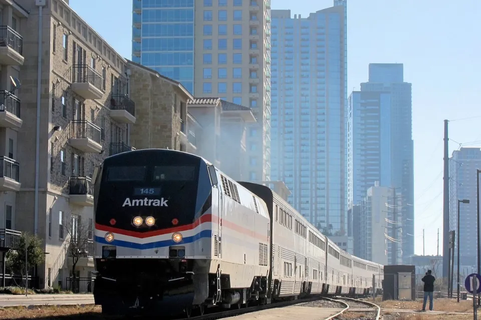 Texas Eagle Amtrak train pulling into station in Austin, Texas with glass high-rise buildings in background.